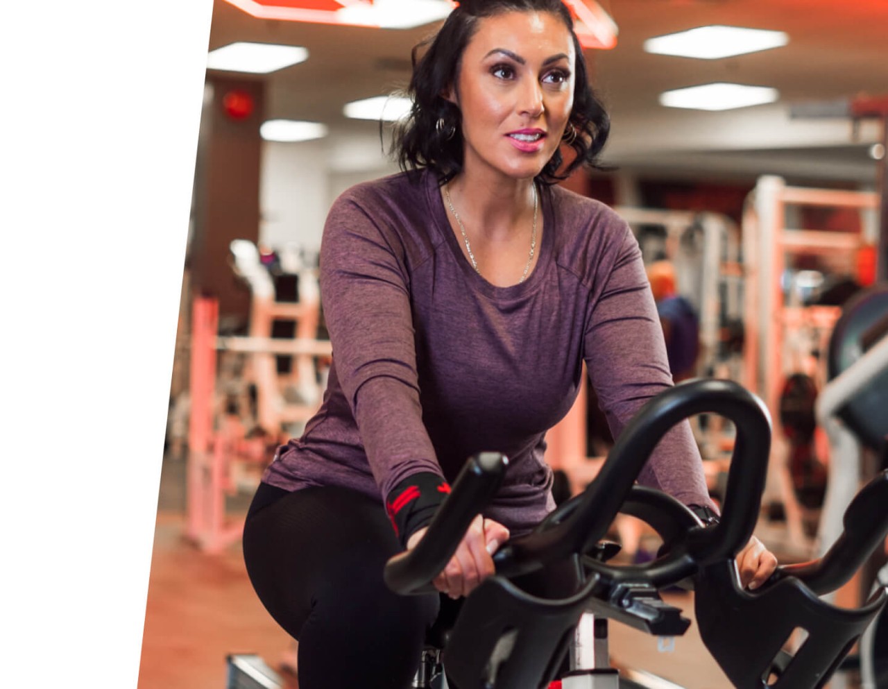 Woman in purple long-sleeved shirt trains on stationary bicycle