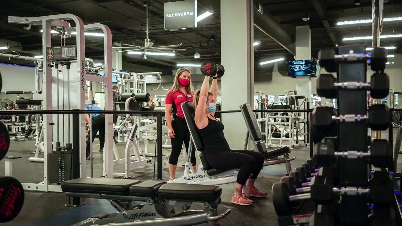 GoodLife Fitness trainer observes a client doing a TRX pushup