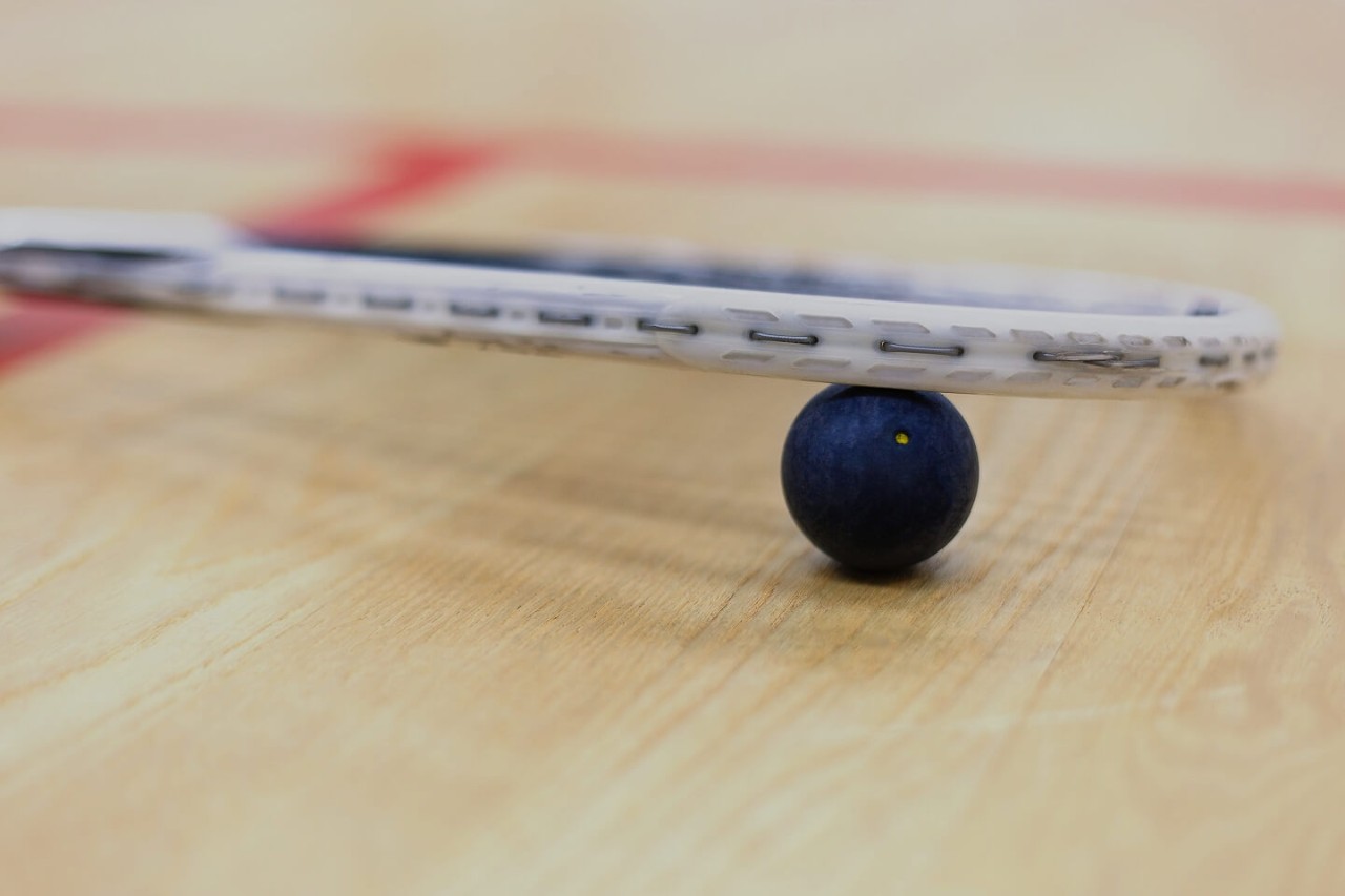 Close-up of a squash ball and racket on a squash court