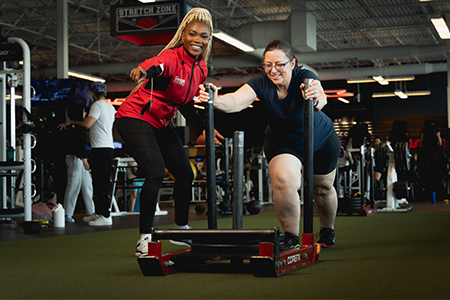 GoodLife Fitness trainer observes a client doing an exercise with medicine ball
