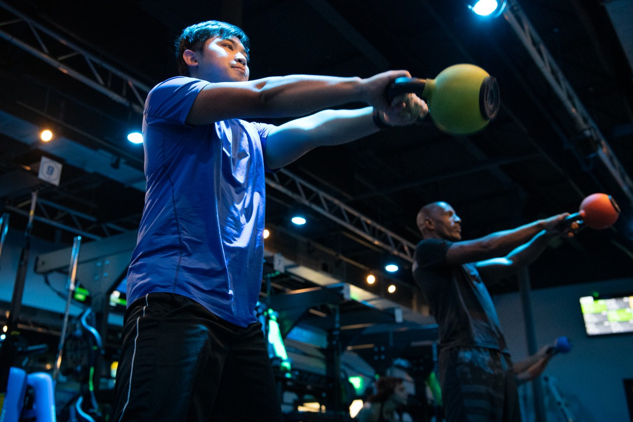 Man in blue shirt exercising with a kettle bell