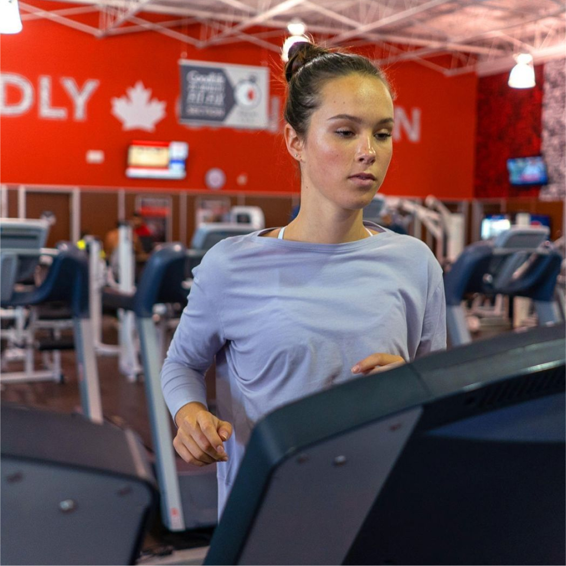 Woman in blue long-sleeved shirt running on treadmill 