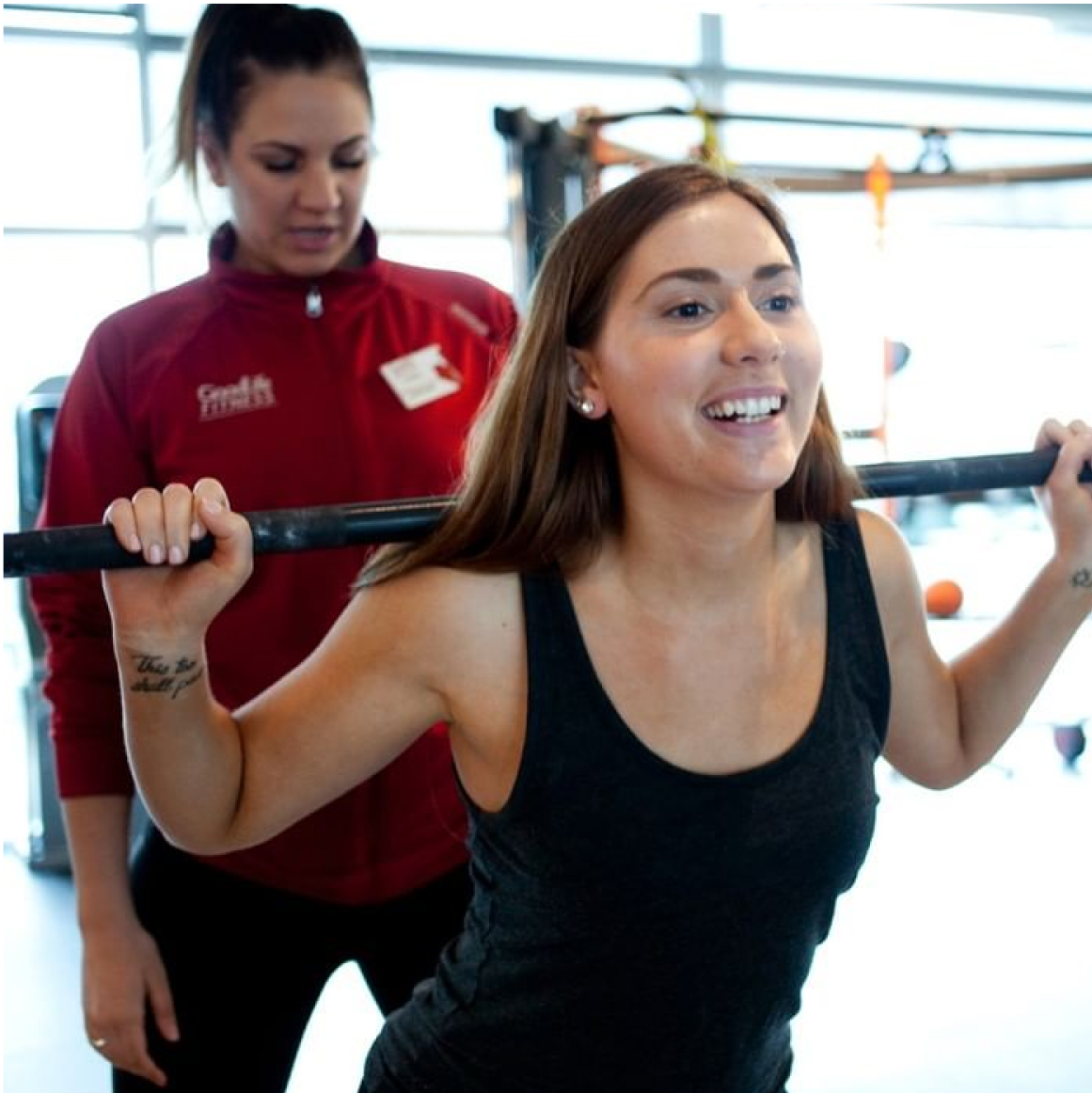 GoodLife trainer observes client’s barbell squat form