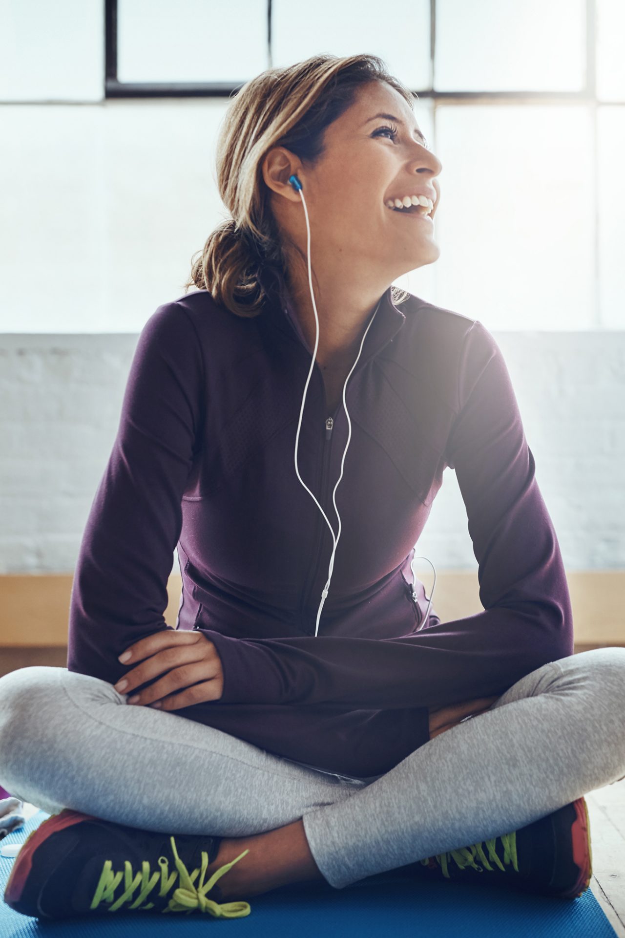 Women in athletic gear sitting with earbuds in. 