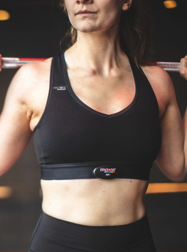 Woman holding barbell on shoulders while wearing MYZONE belt