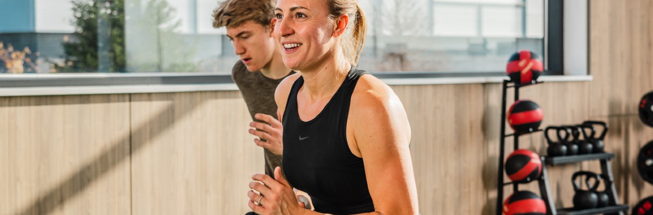 Man and woman mid-squat during a PEAK workout.