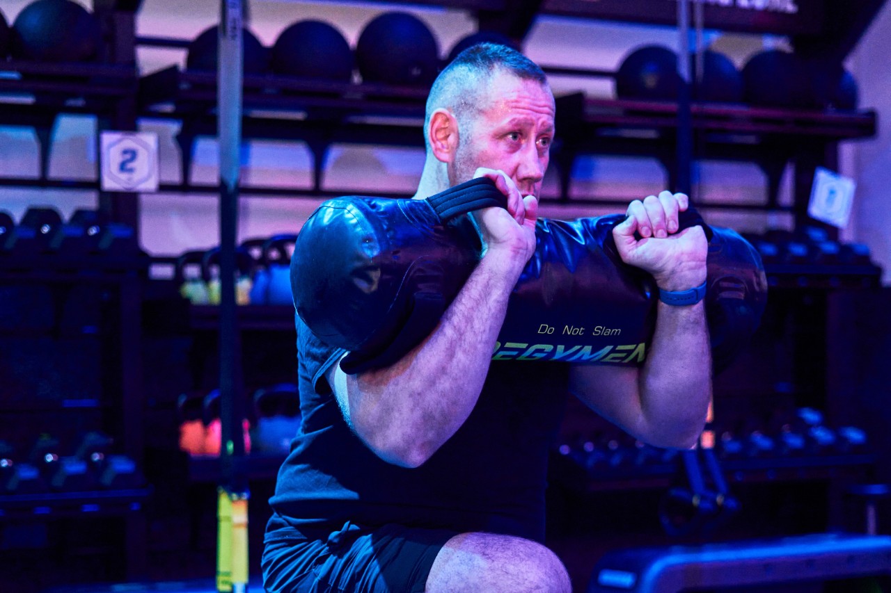 Man and woman in squat position, preparing to catch a medicine ball.