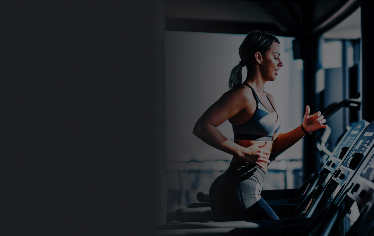 Woman smiling while running on a treadmill in a GoodLife Fitness club