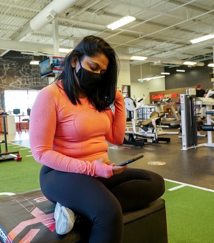 Women in athletic gear sitting with earbuds in. 