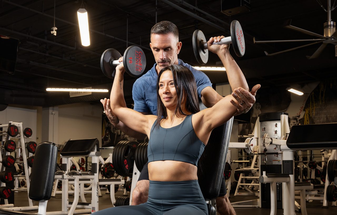 GoodLife Fitness trainer observes a client doing a TRX pushup