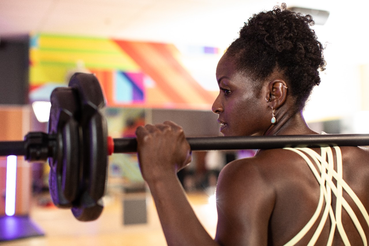 Woman holding barbell on shoulders and looking to the left