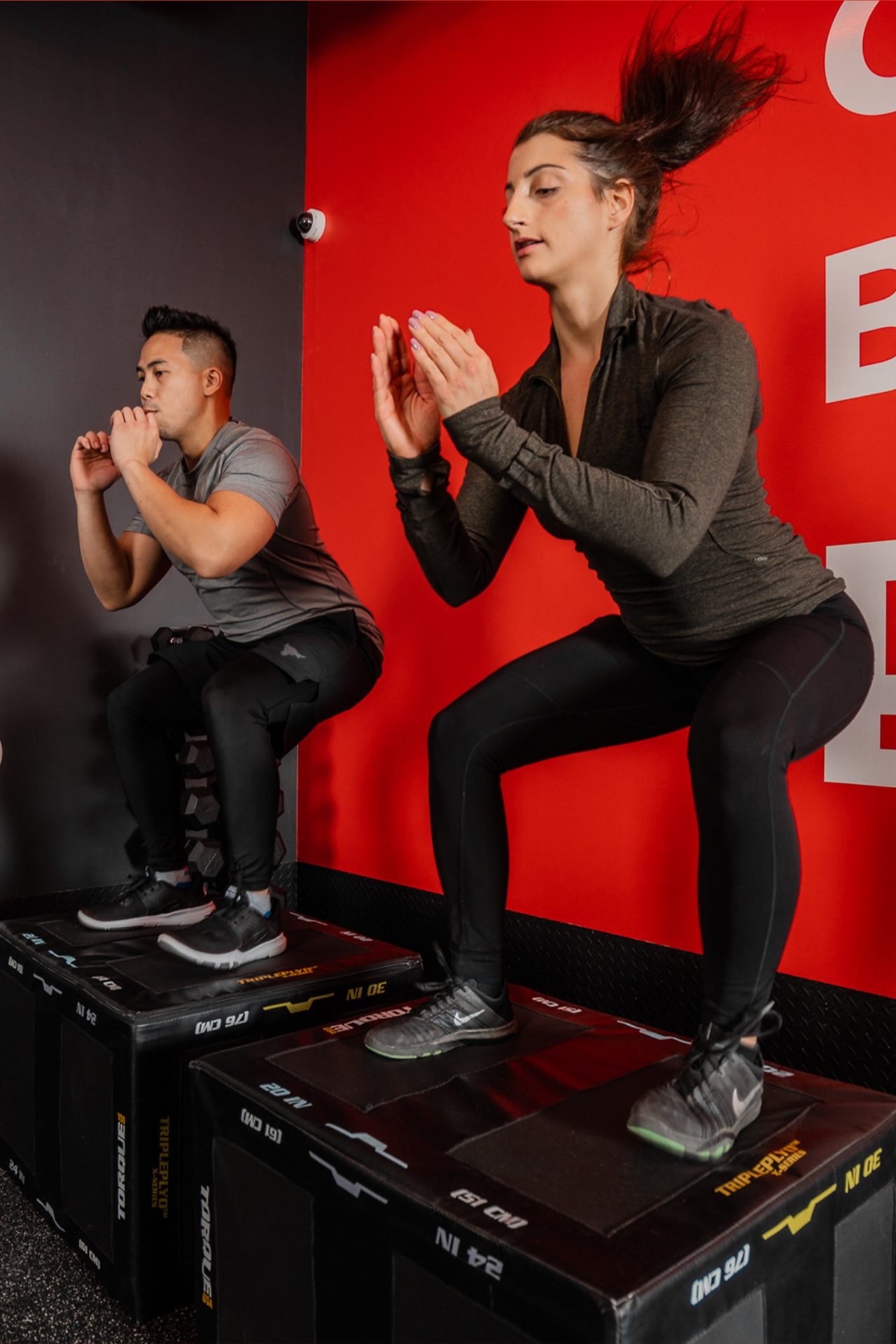 Woman and man doing box jumps onto black boxes