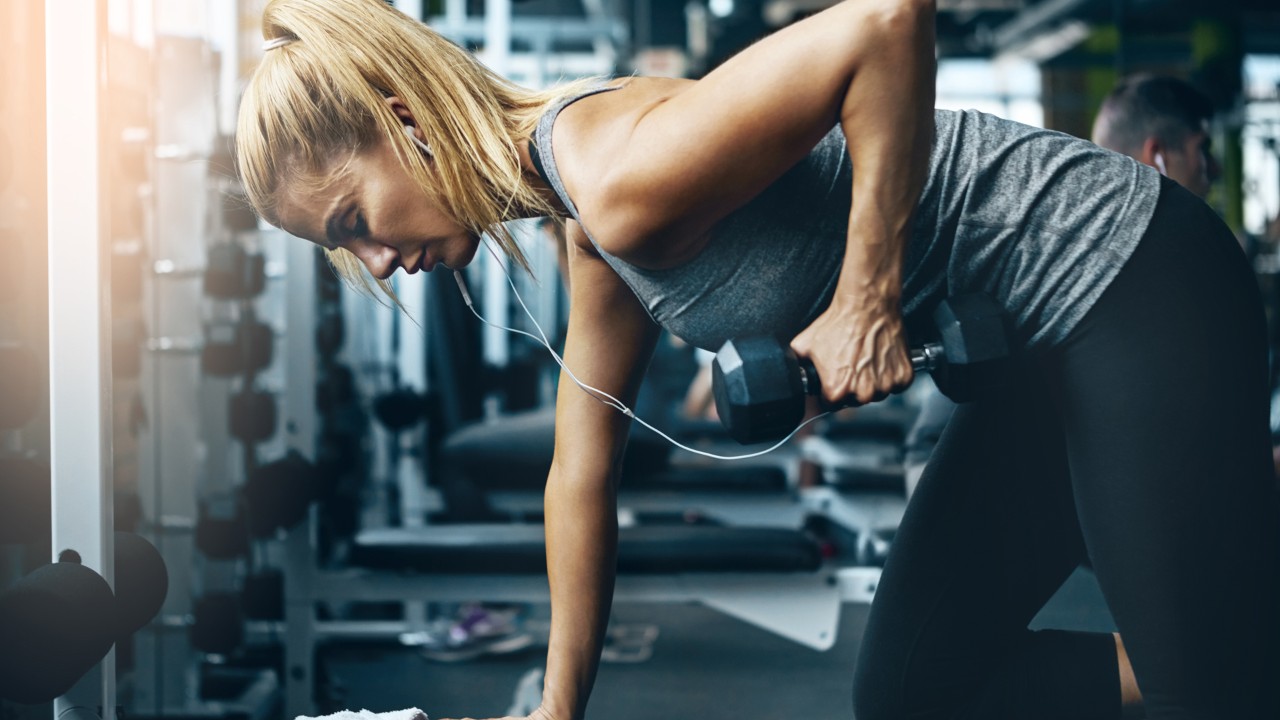 Woman wearing headphones doing single-arm row