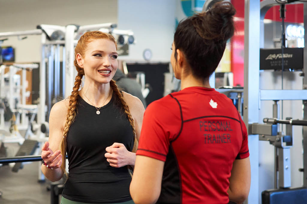 A Member talking with a GoodLife Associate, and another person smiling.