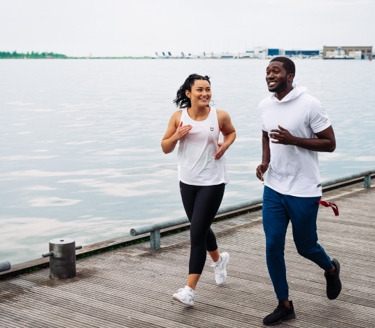 Woman and man running on a dock near water