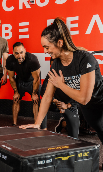 Woman doing a single-arm plank while group looks on in support