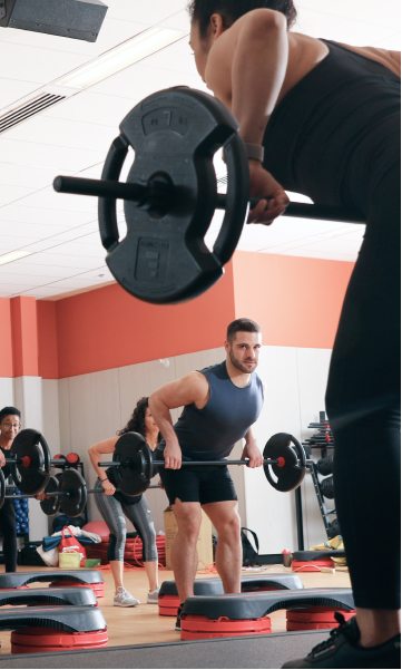 GoodLife fitness instructor leads a group class in barbell row exercises